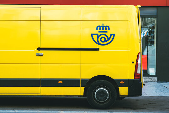 Yellow delivery van of Correos,the Mail Spanish postal company delivering on a public street.Public postal service in Spain