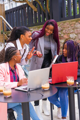 Young and alternative businesswomen of black ethnicity. In a team-building meeting, in a cafeteria with computers