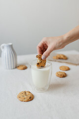 Obraz na płótnie Canvas Female hand dipping cookies in milk. Oatmeal cookies and milk.