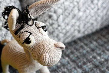 Amigurumi doll is a gray donkey with big eyes.