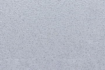 Uneven rough metal surface covered with gray glossy paint.