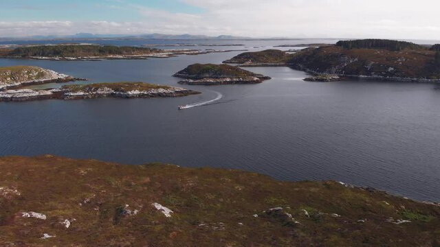 Small boat on the sea between small islands at the norwegian coast. Aerial drone video at Froya Island, Norway.
