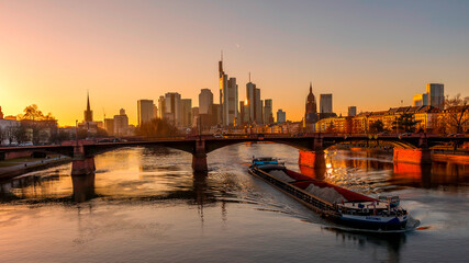 Fototapeta na wymiar The skyline of Frankfurt at sunset, seen from a bridge at the river Main at a cold day in winter.
