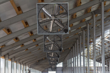 Construction of a complex from a metal frame and sandwich panels. Inside an industrial building. Industrial fans on the roof of the building for blowing off the premises.