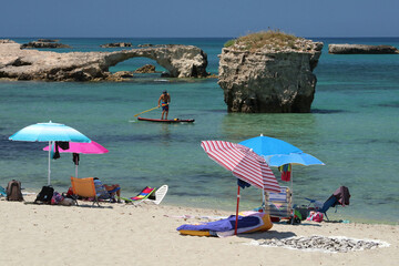 Stand Up Paddle, beach and umbrellas nearby a rocky coast