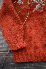 Red woolen handmade baby sweater on gray background