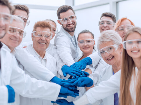 group of medical lab employees joining their palms together.