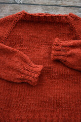 Red woolen handmade baby sweater on gray background
