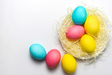 Fototapeta na wymiar Colored Easter eggs in nest isolated on white background. Happy Easter card, copy space, top view