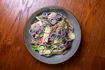 Salad with hard cheese, onions and herbs on a plate. Healthy and tasty food. view from above