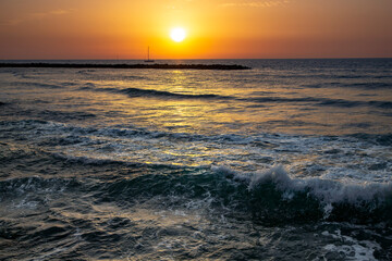 Sailing boat at sunset in orange tones over the Mediterranean sea in Tel Aviv, Israel
