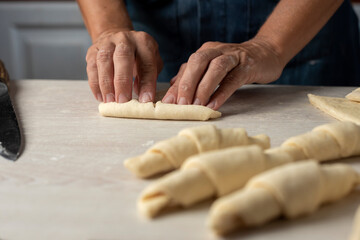 hands assembling and stretching, shaping the croissant dough and croissant into triangles to...