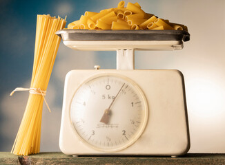 kitchen scale with spaghetti and macaroni on the wooden table