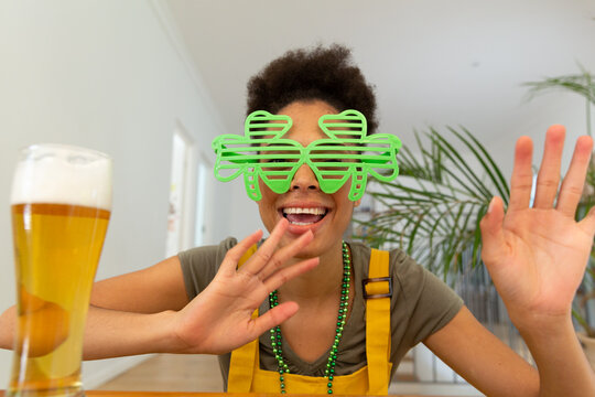 Happy mixed race woman celebrating st patrick's day making video call and waving