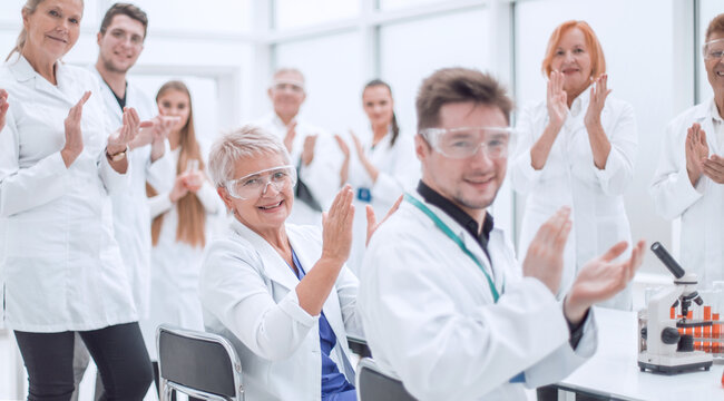 group of young scientists congratulating their colleague with applause