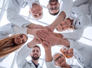 close up. group of different doctors putting their hands together