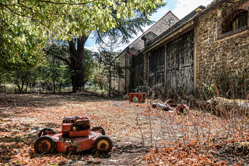 Broken lawn mower in fall grass on a farm