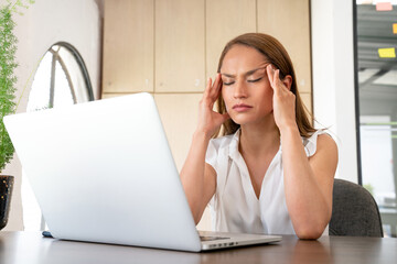 Tired and stressed woman in front of the laptop.