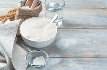 Wheat sourdough, flour and water on a light wooden background. The concept of making bread.