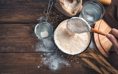 The cook mixes the leaven against the background of wheat flour and water. The concept of making...