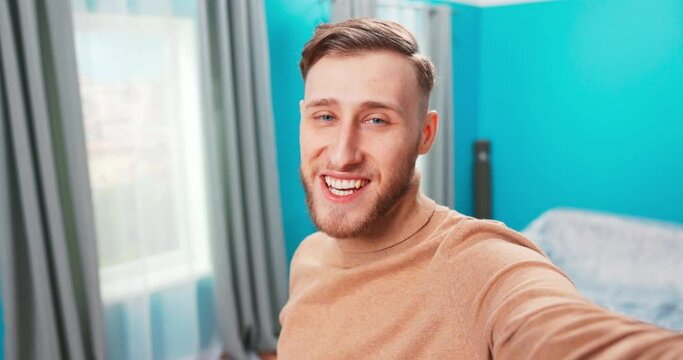 Young man move into new apartment. Man hold camera and talking on it. Showing his new flat during unboxing time. Happy cheerful teenage boy is vlogger.