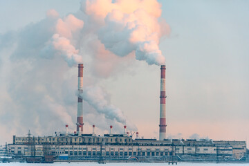Emission smoke to atmosphere from industrial pipes at sunrise. Smokestack pipes of factory in...