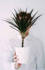 A man holding a plant in front of his head