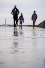 Father and two children walk along a pier in autumn. Defocused