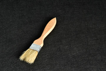 A new, light-colored paintbrush lies on a black background. High quality photo