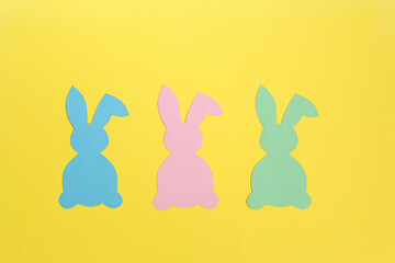 Colorful paper Easter bunnies on a yellow background. Easter and creative concept.