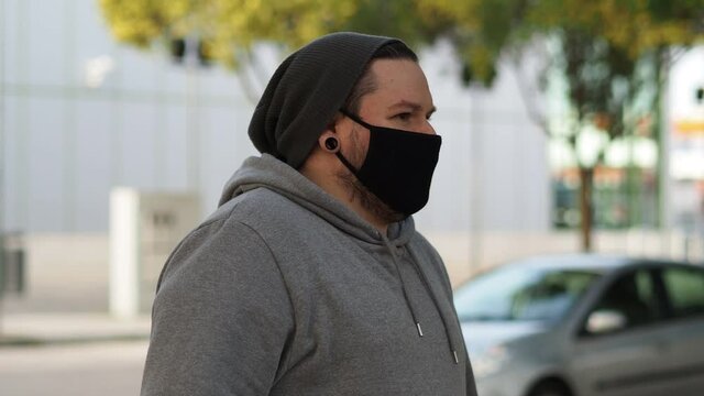 Hombre joven con mascarilla hablando con un amigo durante la pandemia del coronavirus respetando las medidas de seguridad y distanciamiento social