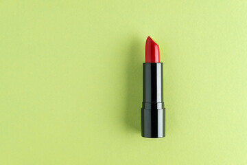 Red lipstick isolated on a light green background.