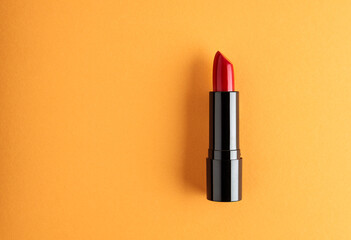 Red lipstick isolated on an orange background. - obrazy, fototapety, plakaty