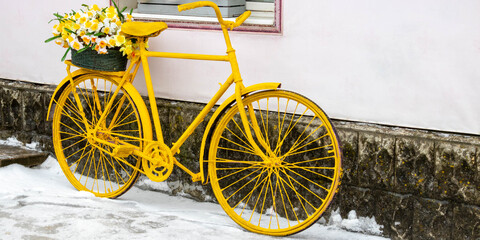 Fototapeta na wymiar An old yellow bicycle stands against a wall in winter, in vintage style