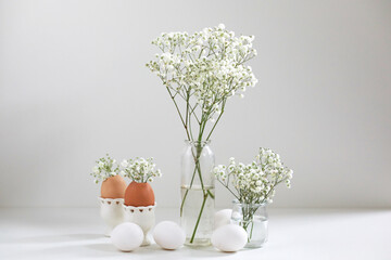 Romantic elegant bouquets with white flowers gipsophila and eggs on light background. Copy space. Easter concept.