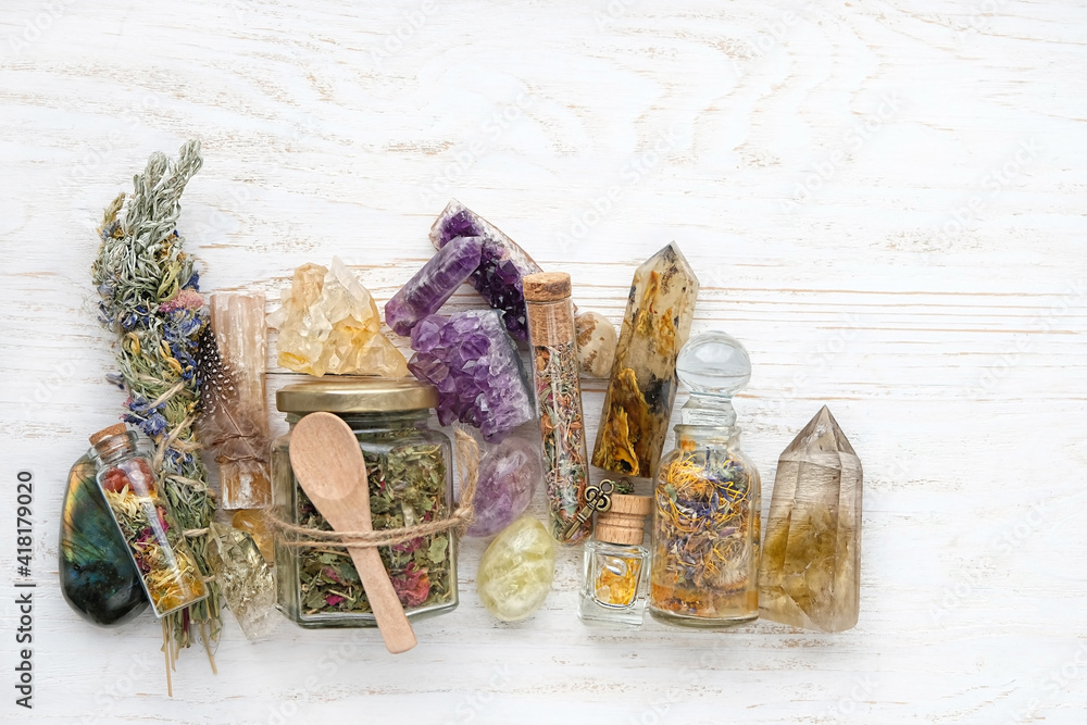 Wall mural healing mineral gemstones, herbal tea in jar, spell bottles on rustic white table. witchcraft things