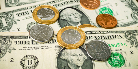 Dinheiro, Real Brasileiro e Dólar americano. Conceito de mercado de câmbio. Moedas do Brasil sobre notas de 1 dólar.