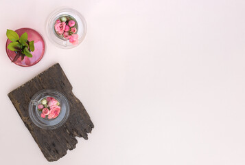 Miniature rosebuds in gglass cups and green leaves in rose vase on pastel background with copy...