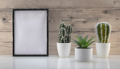 Modèle de cadre photo blanc avec espace vide pour logos, inscription publicitaire. Cadre en mode portrait sur un espace de travail avec des plantes vertes. Ambiance zen.	