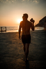 Young male photographer makes photographs of the sea at sunset while standing on the shore. Sea sunset. Selective focus. Tourist photographs the seascape