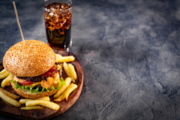French fries and burger on plate near glass with cola
