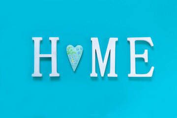 Home, wooden text with heart shape decor on blue background. Concept of building houses, choosing your own house, mortgage, buying, selling residential area, rental, insurance, investment real estate.