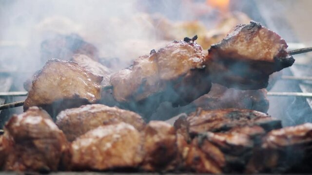 Shish Kebab on Skewers is Cooked on the Grill at Street Food Festival. Close-up. Cook grill turns skewers. Pieces of pork roasted. BBQ. Prepares meat on coals. Street kitchen. Fresh grilled food.