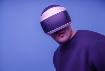 A man in his thirties wearing virtual reality glasses playing video games with a virtual reality headset Fashionable Neon Tinted. Copy space