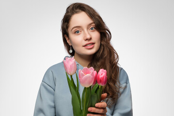 Young woman with tulips. Blue eyes, long hair and surprise on her face.