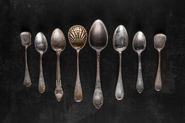 Silver cutlery on black background.Pile of vintage silverware and empty plates on dark grey...