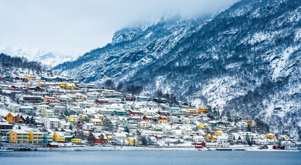 wooden houses on the banks of the Norwegian fjord, beautiful mountain landscape in winter
