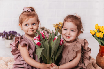 Two beautiful girls with a bouquet of tulips smile
