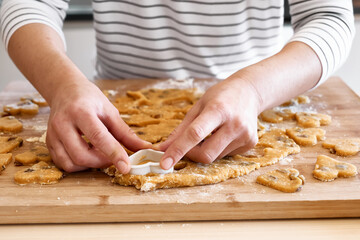 Woman making heart shaped cookies on the table in the kitchen. Gluten free flour cookies. Homemade healthy eating.