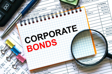 Obraz premium The notebook with the text Corporate Bonds lies on the financial tables with a calculator a magnifying glass